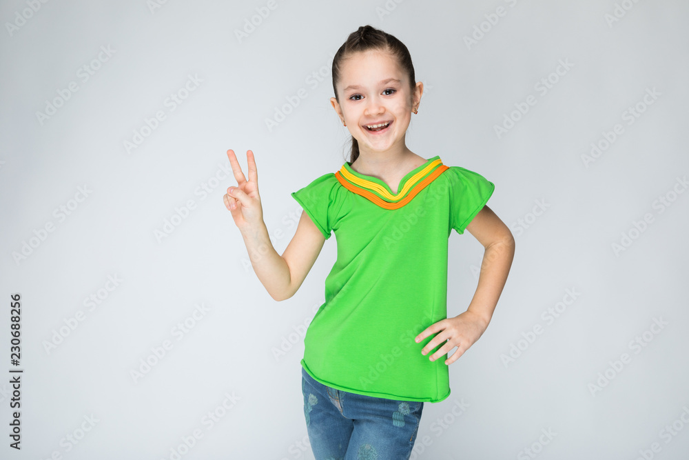 The girl on a gray background shows two fingers. The girl on a gray background shows two fingers.