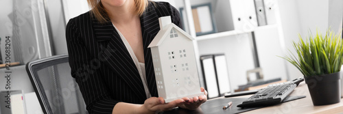 A young girl sitting at a table in the office and holding the layout of the house. photo