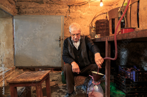 Foto The old man stands in the old wine cellar and boasts wine in bottles