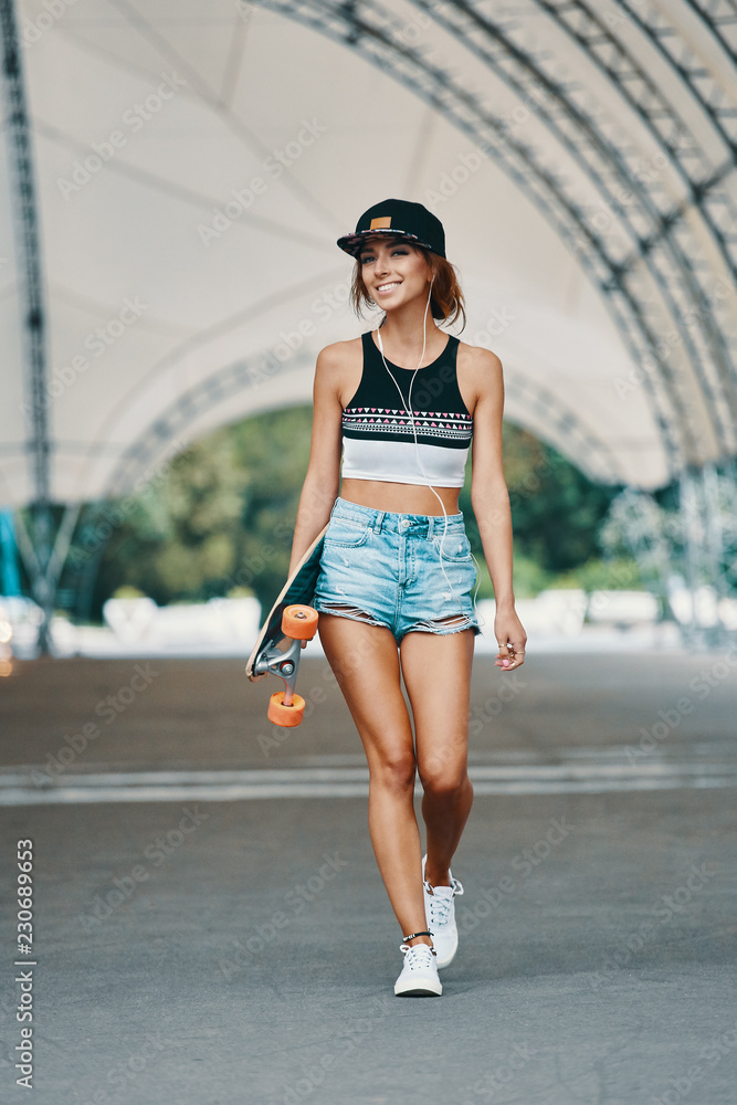 Fototapeta premium Young pretty smiling girl with a longboard