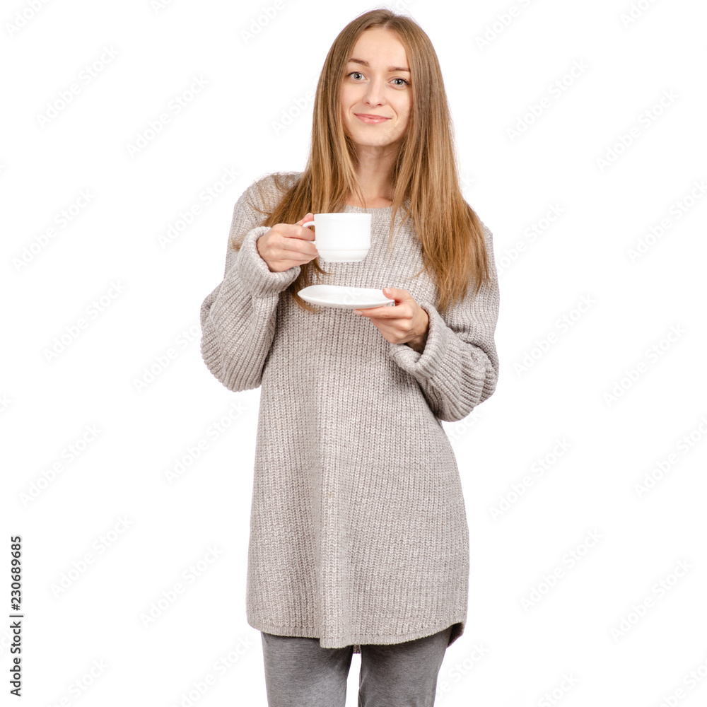Young woman in sweater holding a white cup and saucer in hands, drinking hot coffee on white background. Space for your logo or text. Young woman in sweater holding a white cup and saucer in hands, drinking hot coffee on white background. Space for your logo or text.