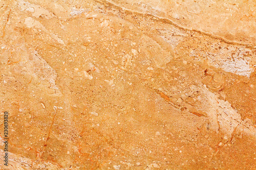 Orange marble texture background. Natural marble stone texture in warm colors. Background with small waves and a round pattern. Brown, orange, gold, yellow and beige shades.