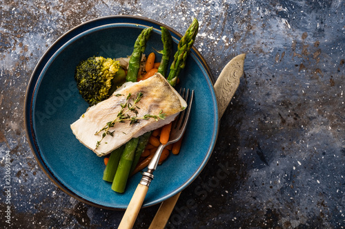 Pike perch fillet with asparagus, broccoli and carrots. Fried fish with stewed greens