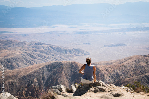 A girl viewing over Joshua Tree National Park with its typical trees and rock formations near Palm Springs in the California desert in the USA 