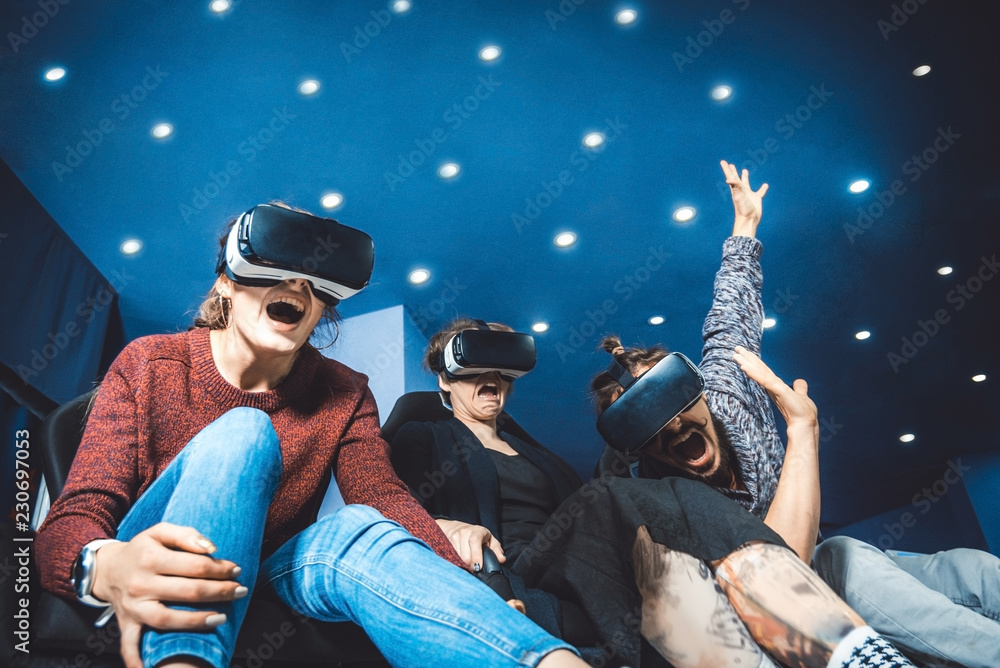 friends in virtual glasses watching movies in the cinema with special effects in 5d - obrazy, fototapety, plakaty 