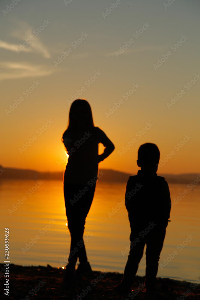 Brother and sister on the beach watching the sunset