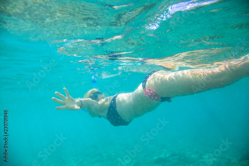 underwater female in apnea with american flag bikini. Underwater scene of a female apnea and doing skin diving. Watersport activity in Hawaii. Tropical destination holiday travel concept.
