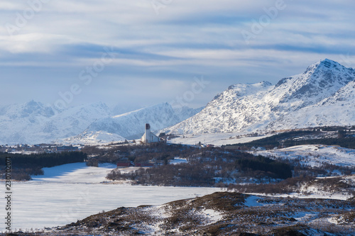 The Borge church near Bøstad surrounded by snow-covered mountains of Vestvågøy, Lofoten, Norway photo