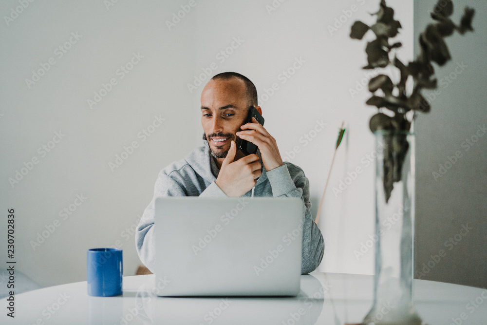 .Young and attractive man working from home with his laptop and making calls, having a coffee in the morning with comfortable clothes. Networking. Lifestyle. .Young and attractive man working from home with his laptop and making calls, having a coffee in the morning with comfortable clothes. Networking. Lifestyle.