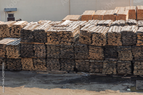 Piles of wooden planks at the seaport berth. Warehouse for sawing in stacks for loading in the open air. Material wooden wooden blanks. Industry.