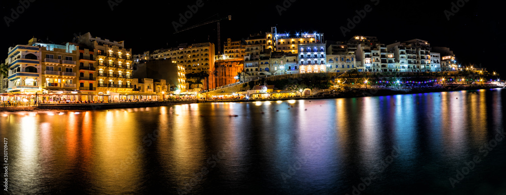 Colorful light reflections.  Seaside resort town of Xlendi at night.  This town right off the Mediterranean Sea is located on the island of Gozo, Malta.