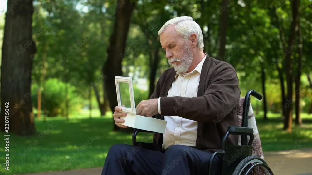 Disabled grandfather looking at military token in white box, homeland merits Disabled grandfather looking at military token in white box, homeland merits