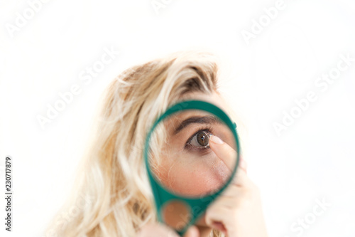 young beautiful girl of European appearance under a magnifying glass puts a lens on the eye