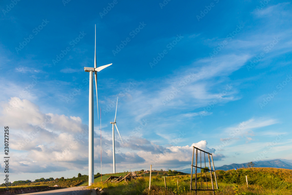 White wind turbine for alternative energy in day with blue sky background, electric clean power concept White wind turbine for alternative energy in day with blue sky background, electric clean power concept