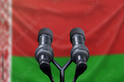 Podium lectern with two microphones and Belarus flag in background photo