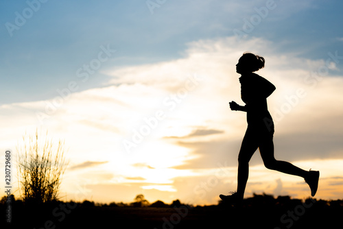 silhouette woman running alone at beautiful sunset in the park.