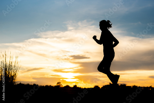 silhouette woman running alone at beautiful sunset in the park. © stcom