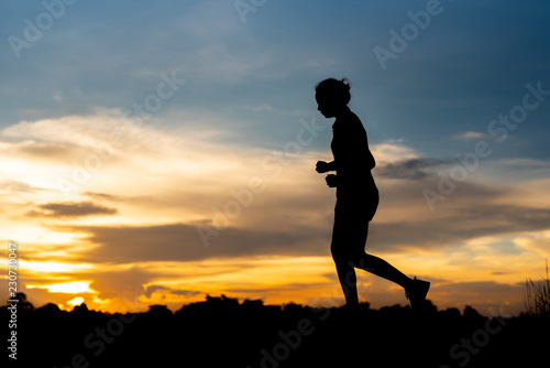 Fototapeta Naklejka Na Ścianę i Meble -  silhouette woman running alone at beautiful sunset in the park.