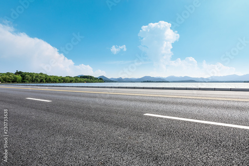 Asphalt road and beautiful mountain with lake under the blue sky