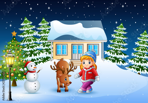 Cute little girl with a deer in front of snowy house in christmas day