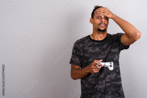 Young bearded handsome African man against gray background