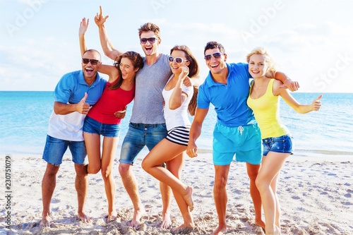 Female hands taking photo of group of people standing on beach