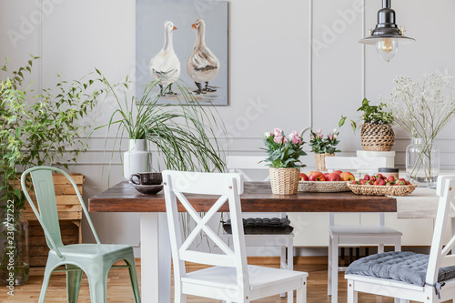 Rustic dining room with long table and white chairs and oil painting on the grey wall, real photo photo