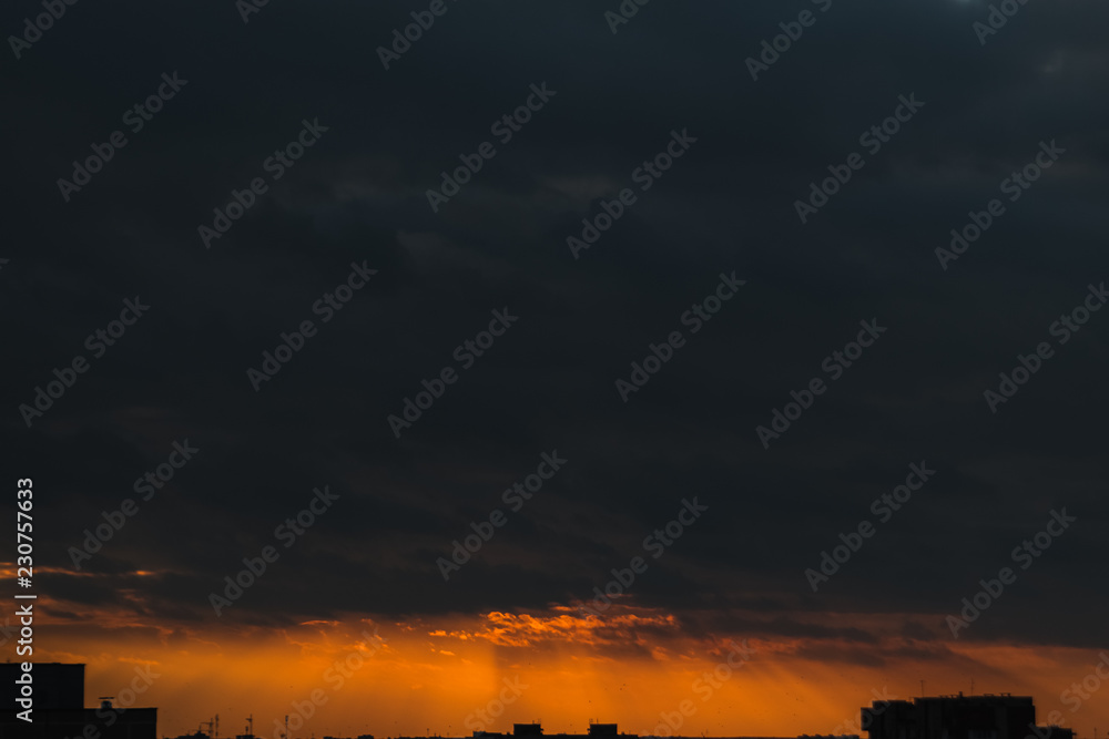 Creative background, orange sunset, rain clouds, clouds. Evening light, before a thunderstorm.