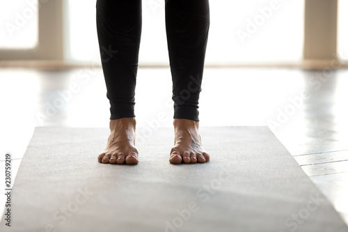 Sporty yoga woman doing leg and foot strengthen exercise, standing pose, working out wearing sportswear grey pants, indoor close up, at white at yoga studio. Healthy hobby well being activity concept