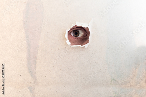 Frightened eye looking true the hole in paper