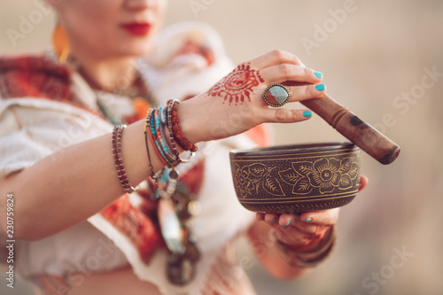 concept. Woman playing a Tibetan bowl. Pregnant woman doing yoga in the field at sunset.