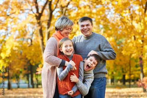 Happy family walks in autumn city park. Children and parents posing, smiling, playing and having fun. Bright yellow trees.