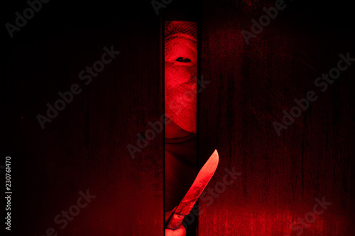 Serial killer / eye peeking behind the door with kinfe