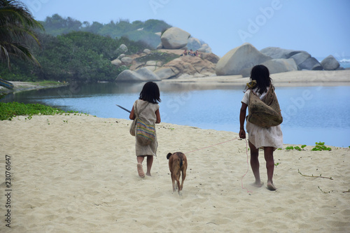 Kids of indigenous tribe walking with a dog on the beach, Tayrona, Colombia photo