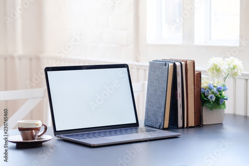 Mockup laptop and books with coffee on office desk.