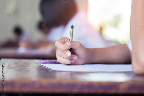 Close-up hand of students writing an exam in classroom with stress