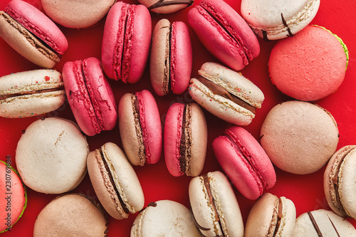 Macaroons on colored background, a lot of colorful french cookies macarons. Beige, brown french cookies macarons on red background. Gift for Valentine's Day
