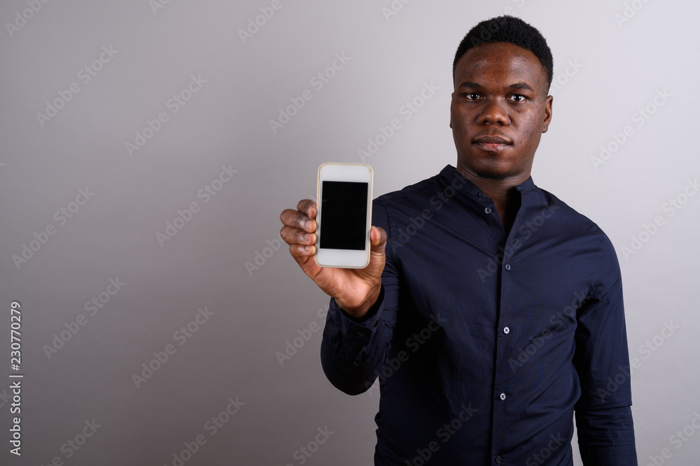 Young African businessman with mobile phone against white backgr Young African businessman with mobile phone against white backgr