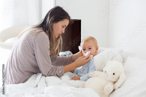 Fotografiet Mother and baby in pajamas, early in the morning, mom taking care of her sick to