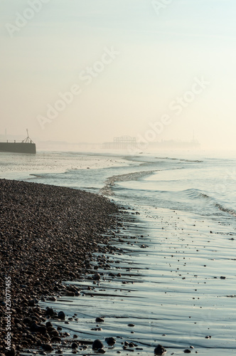 Slika na platnu Skeletal West Pier appearing through sea mist at low tide on Brighton beach