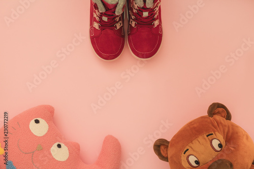 Burgundy women's winter boots for children on a pink background with children's toys, copyspace, flatlay