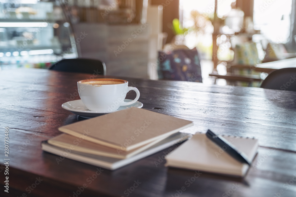 Notebooks, pen and coffee cup on wooden table in cafe Notebooks, pen and coffee cup on wooden table in cafe