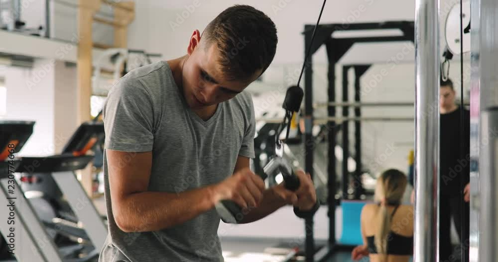 Young beginner man exercising in gym training with training apparatus Young beginner man exercising in gym training with training apparatus