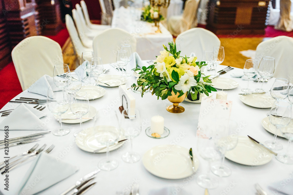 Fototapeta premium Wedding table set up. Indoor set up of a wedding/party table with flower decoration
