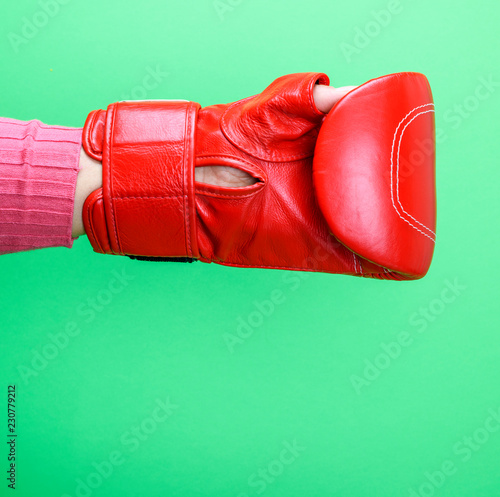  hand is wearing a red leather boxing glove on a green background © nndanko