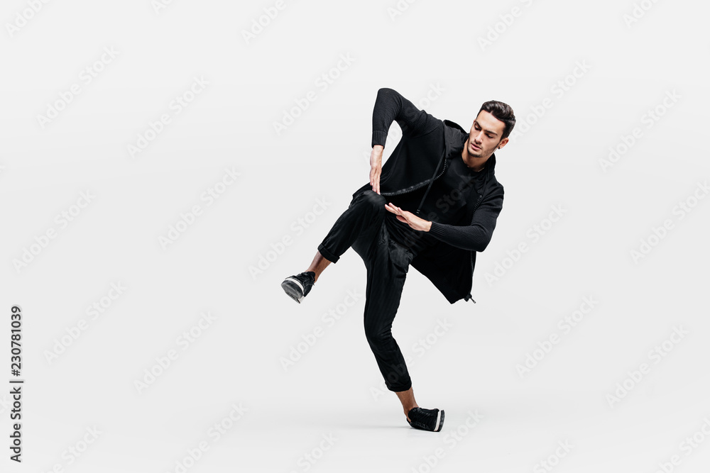 Handsome young man wearing a black sweatshirt and black pants is dancing breakdance