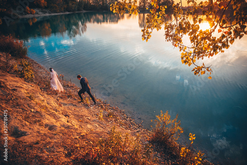 Wedding couple, autumn evening by blue lake