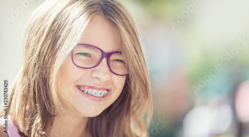 Happy smiling girl with dental braces and glasses. Young cute caucasian blond girl wearing teeth braces and glasses