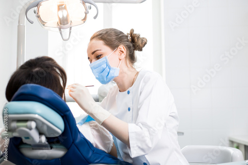 Dentist in uniform treats the patient s teeth in the white office