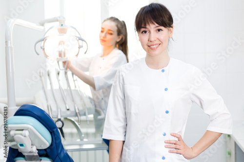 Two girls dentists at the workplace  the dentist in the background preparing equipment for the reception of the patient